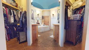 Bathroom with a walk in closet, a bath, and vanity