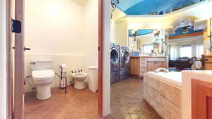 Full bathroom featuring a bidet, vanity, and washer and clothes dryer