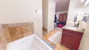 Bathroom featuring double vanity, a garden tub, and light wood-style flooring