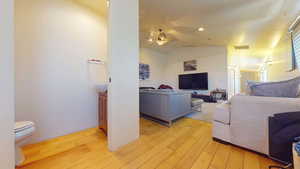 Living area featuring vaulted ceiling, light wood-style floors, a ceiling fan, and recessed lighting