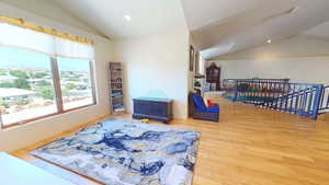 Sitting room with vaulted ceiling, wood finished floors, recessed lighting, and an upstairs landing