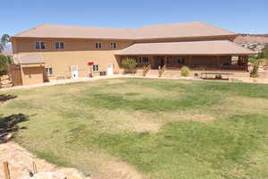 Rear view of house with covered porch, a tiled roof, stucco siding, and a yard