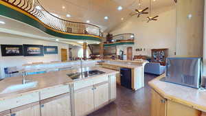 Kitchen with light brown cabinetry, open floor plan, high vaulted ceiling, recessed lighting, and black appliances