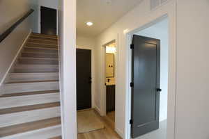 Stairway with wood finished floors and recessed lighting
