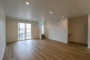 Spare room featuring light wood-style flooring, recessed lighting, and stairway