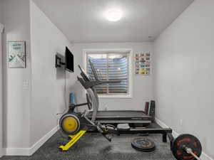 Exercise area featuring a textured ceiling and baseboards