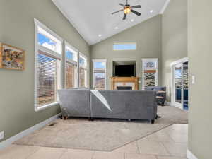 Living room with light colored carpet, light tile patterned floors, high vaulted ceiling, a fireplace, and recessed lighting