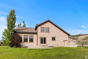 Rear view of house with a lawn, roof with shingles, and entry steps