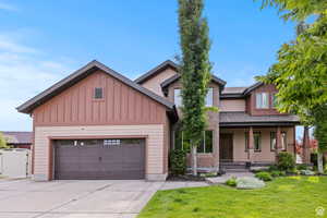 Craftsman-style home with covered porch, driveway, board and batten siding, a front lawn, and an attached garage