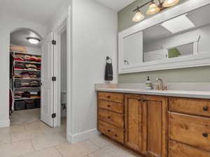 Full bathroom featuring vanity, a walk in closet, and light tile patterned floors