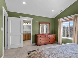 Bedroom with light colored carpet, recessed lighting, lofted ceiling, ensuite bath, and light tile patterned floors