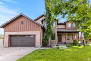 Craftsman inspired home with covered porch, a front lawn, board and batten siding, concrete driveway, and roof with shingles