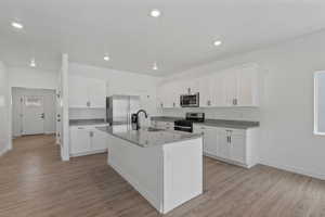 Contemporary kitchen featuring white cabinetry, granite countertops, and stainless steel appliances