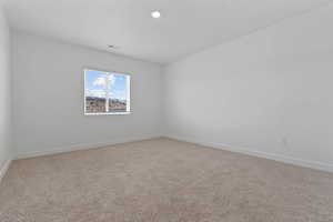Neutral-toned carpeting grounds this room featuring white walls and a single window with blinds