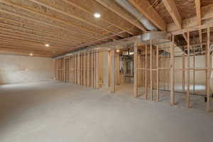 Unfinished basement with exposed wood framing, concrete flooring, recessed lighting, and visible HVAC ductwork