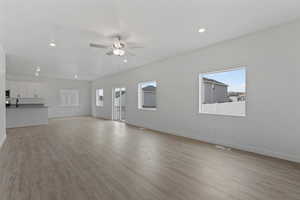 Expansive open-concept living space featuring wood-finish flooring, recessed lighting, and a ceiling fan