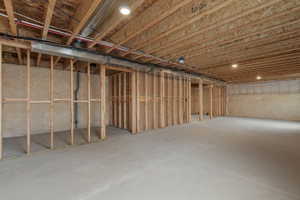 Unfinished basement featuring extensive wood framing, concrete flooring, exposed ceiling joists, and recessed lighting