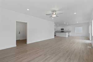 Open-concept living space featuring wood-finish flooring, recessed lighting, and a ceiling fan