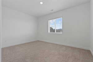 Carpeted interior space featuring a window with blinds, recessed ceiling lighting, and white walls with matching baseboards
