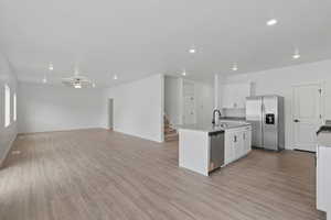 Contemporary kitchen featuring a center island with sink, stainless steel appliances, white cabinetry, and granite countertops