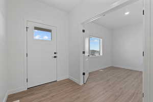 Entryway with a white paneled door featuring a clear glass insert and matte black hardware