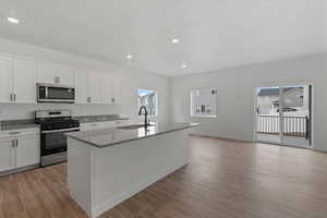 Modern kitchen featuring white cabinetry, stainless steel appliances, and granite countertops