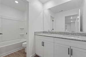 Bathroom featuring a double vanity with stone countertops, undermount sinks, and contemporary fixtures