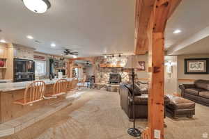 Living room featuring a stone fireplace, light carpet, a textured ceiling, and recessed lighting
