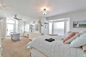 Bedroom with light colored carpet, a textured ceiling, lofted ceiling, and a ceiling fan