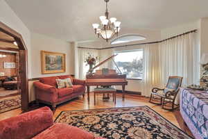 Living room featuring a chandelier, light wood-type flooring, and lofted ceiling