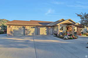 View of front of home with an attached garage, concrete driveway, a shingled roof, and brick siding
