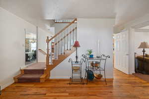 Stairs with wood finished floors and a chandelier
