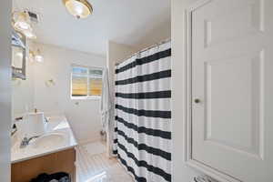 Full bathroom featuring double vanity and curtained shower