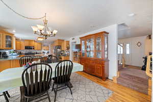 Dining space with light wood finished floors, a chandelier, and stairs