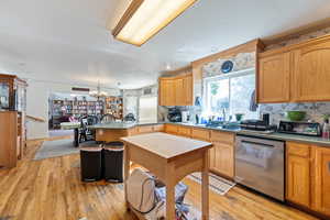 Kitchen featuring a peninsula, dishwasher, light wood-style floors, a chandelier, and pendant lighting