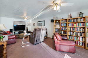 Living area with ceiling fan, carpet, and a textured ceiling