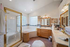 Bathroom featuring a shower stall, a garden tub, double vanity, lofted ceiling, and recessed lighting