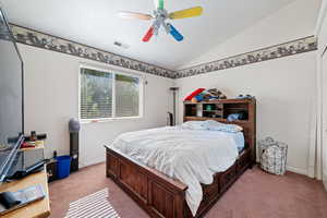 Carpeted bedroom featuring vaulted ceiling and ceiling fan