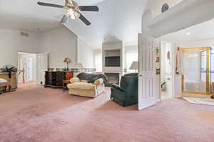 Living area featuring a glass covered fireplace, carpet floors, ceiling fan, high vaulted ceiling, and a textured ceiling