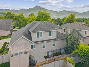 Rear view of house featuring stucco siding, a fenced backyard, roof with shingles, and a mountain view