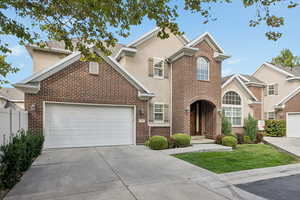 Traditional home with driveway, brick siding, and a garage