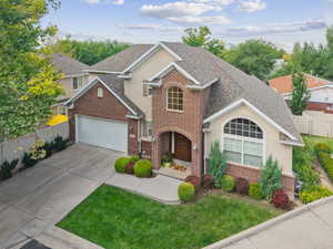 Traditional-style house with brick siding, stucco siding, and driveway