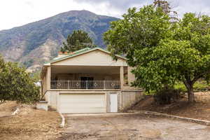 View of front facade with a mountain view, dirt driveway, brick siding, and a garage