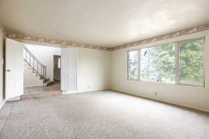 Unfurnished room featuring light carpet and stairs