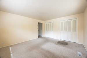 Unfurnished bedroom featuring two closets and carpet