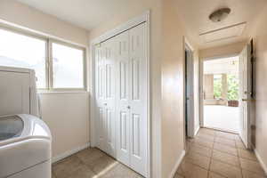 Laundry area featuring light tile patterned floors, washer / clothes dryer, and attic access