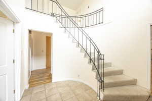 Staircase with tile patterned flooring and a towering ceiling