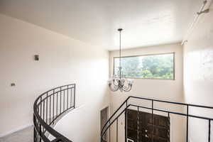 Staircase featuring a chandelier and carpet