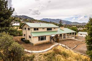 Back of property with a mountain view, brick siding, a metal roof, a chimney, and a standing seam roof