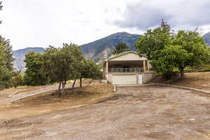 View of front of property featuring a mountain view, a porch, dirt driveway, and an attached garage